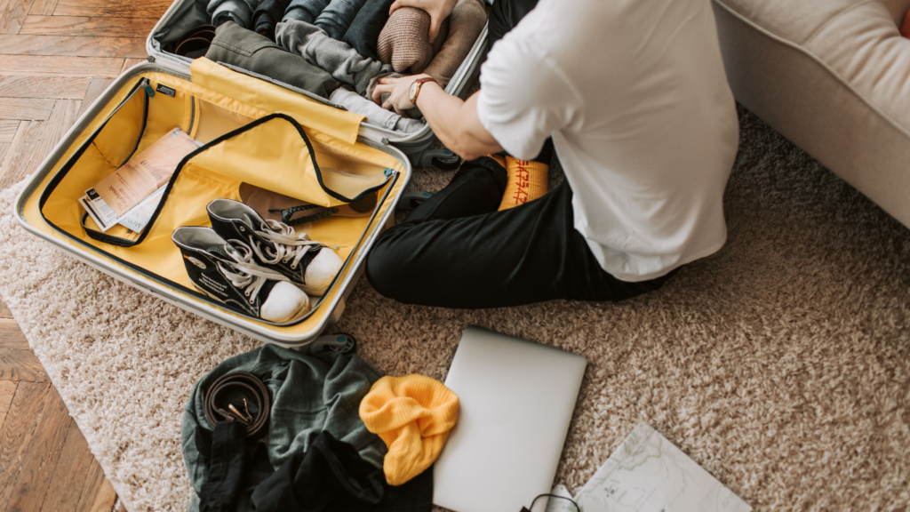 A person sitting on the floor with a suitcase full of clothes