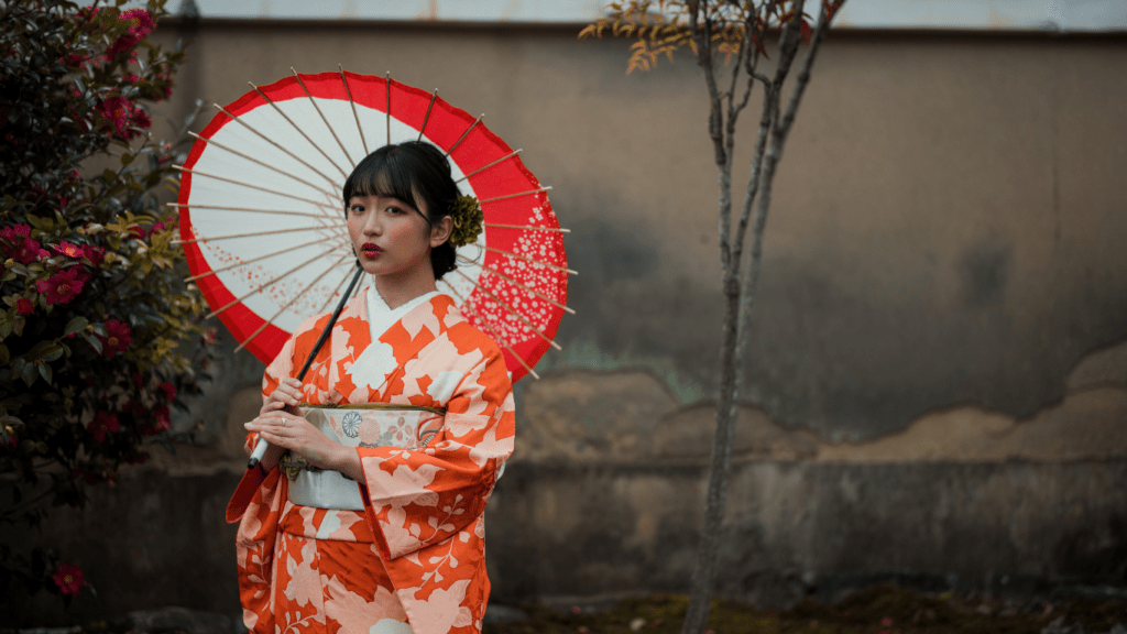 a person in an orange kimono holding an umbrella
