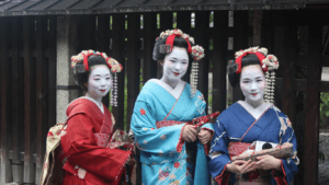 three people dressed in kimono walking down a street