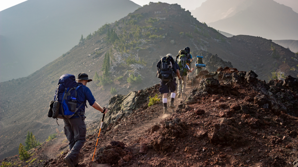 a group of people with backpacks hiking up a mountain