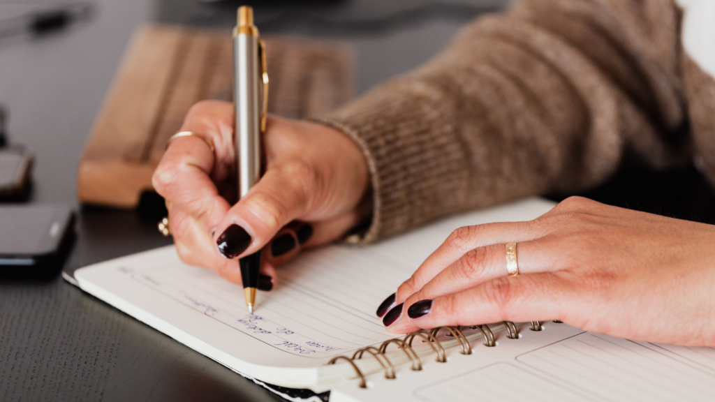 a person is writing in a notebook with a pen