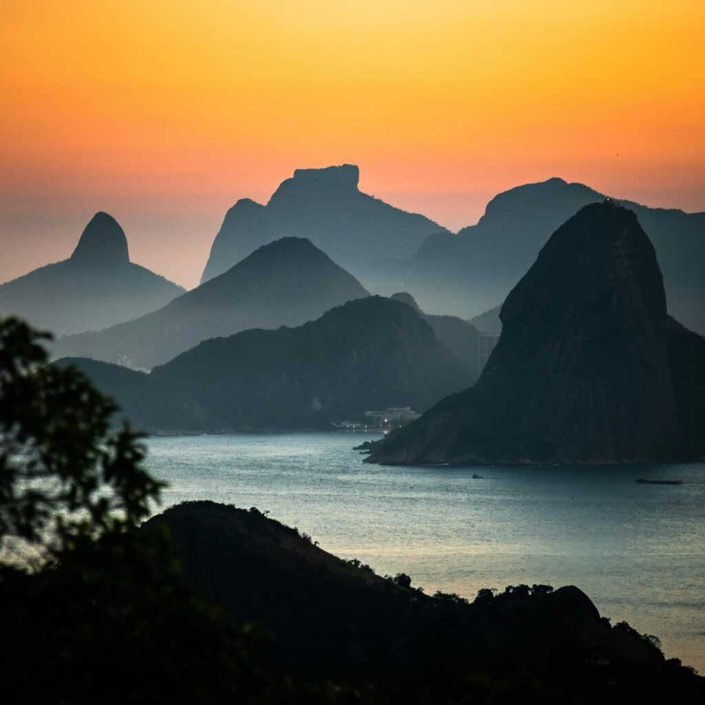 Captivating sunset view of silhouettes of mountains and coastline in Rio de Janeiro.